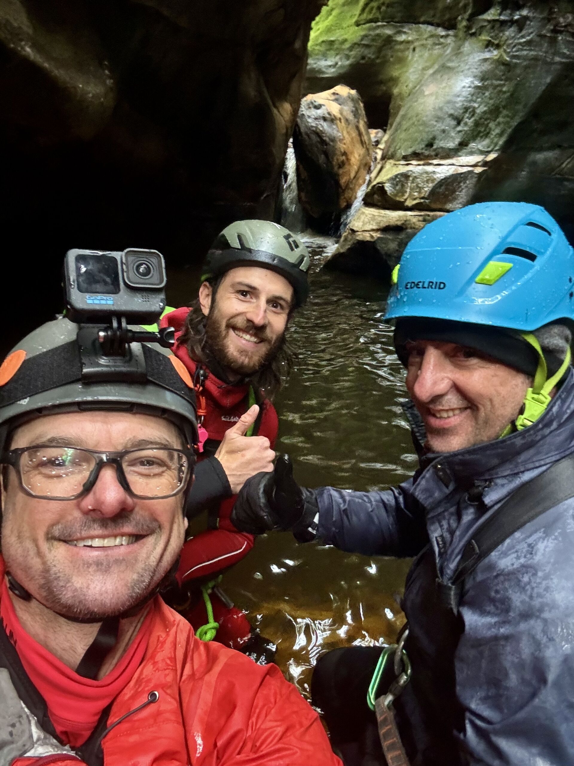 Three canyoners wearing Helmets in a wet canyon. They are all looking very happy. One has a GoPro on his helmet. You would not know, but ine is paraplegic, and the other two his guides on an accessible adventure